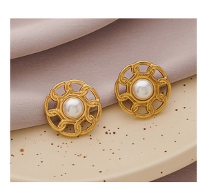 Close-up of vintage gold-plated earrings with central white pearl on a lavender fabric