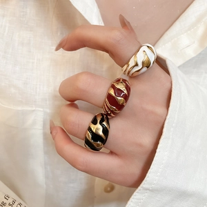 Chunky enamel rings set in white, burgundy, and black with irregular gold wave textures