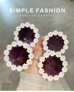 Detail of two white daisy-shaped sunglasses with yellow centers and purple lenses