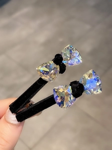 Close-up of black velvet bow hair clips with sparkling iridescent triangle crystals