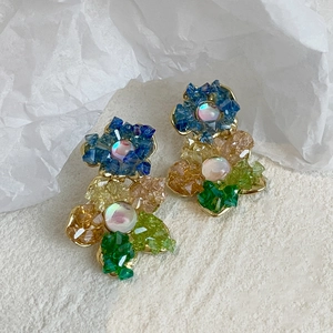 Détail macro de boucles d'oreilles fleur en cristal avec pétales pastel et perle