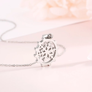 Detailed close-up of a silver snowflake pendant with gear frame on a stainless steel necklace