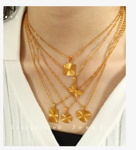 Detail of layered 18K gold plated stainless steel necklaces with sunburst engraved pendants