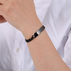 Close-up of a black stainless steel bar bracelet worn on wrist with a white shirt