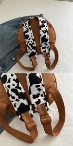 Detail of brown suede backpack with cow print straps and adjustable metal buckles