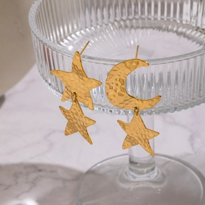 Gold plated stainless steel star and moon earrings with hammered texture on glass stand