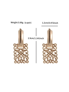 Macro shot of rose gold geometric hollow earrings with detailed vintage patterns