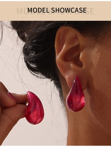 Gros plan de boucles d'oreilles goutte d'eau rouges en résine portées par un mannequin