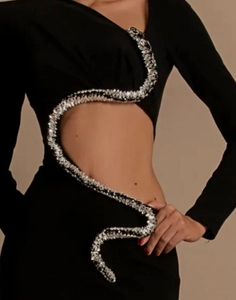 Detail of black dress featuring waist cut-out and sparkling snake-shaped diamond decoration