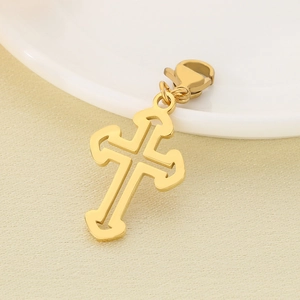 Macro shot of gold hollow cross pendant with lobster clasp on a light beige surface