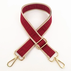 Detail of red and beige geometric woven wide shoulder strap with golden metal clasps