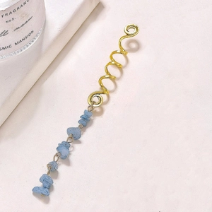 Detail of gold spiral hair pin with hanging irregular blue natural stone charms