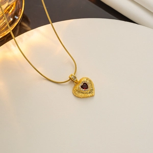 Detailed view of 18k gold heart necklace with red gemstone inlay and sparkly small diamonds