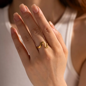 Close-up of a wavy 18k gold plated open ring on model showing curved polished texture