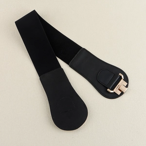 Detail of black elastic wide waist belt with gold geometric metal buckle and PU leather