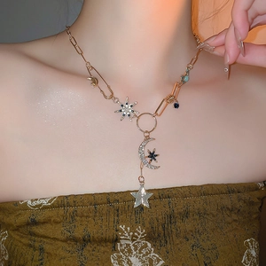 Détail du collier doré avec pendentifs étoile et lune sertis de zircons sur modèle