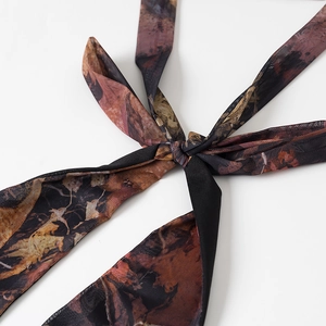 Detail of mesh fabric dress featuring retro abstract print and tie-knot design
