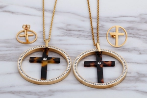Macro detail of gold necklace and earrings set featuring tortoiseshell cross with rhinestones