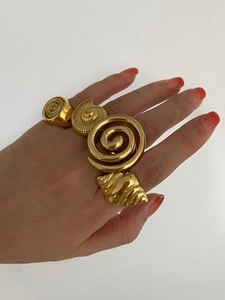 Detailed view of four chunky gold nautilus shell and spiral statement rings on a model