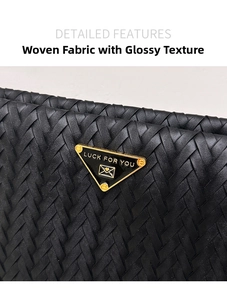 Macro detail of black woven tote bag featuring a gold-edged triangle metal logo