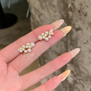 Elegant gold plated flower pearl stud earrings with zircon shown on fingers