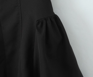 Nahaufnahme der plissierten Schulter und feinen Nähte an diesem schwarzen Kleid