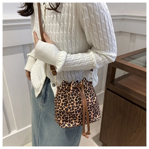 Détail d'un sac seau léopard avec bandoulières en cuir marron et fermeture à cordon