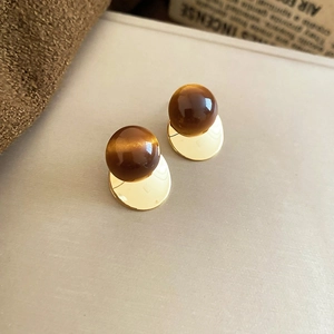 Detail view of 18k gold plated bird earrings with tiger eye stone and tassel accents