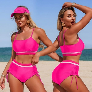 Two-piece hot pink sporty bikini set with drawstring shorts and matching sun hat on beach