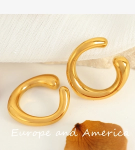 Detailed view of minimalist golden C-shaped clip-on earrings on natural decor