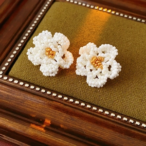Macro shot of French vintage beaded camellia earrings on green velvet and wooden frame