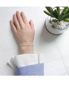 Close-up of a minimalist silver double-layer snake chain bracelet on a female wrist
