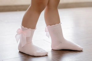 Detail of pink cotton princess socks with silk bow and ruffled edges for little girls
