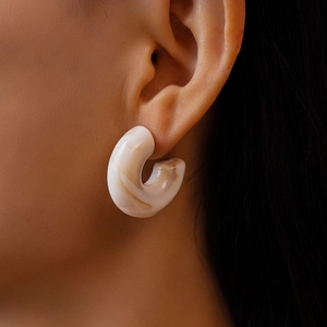 Detailed view of beige marble acrylic C-shaped earrings on model with high gloss finish