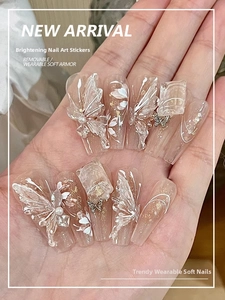 Dettaglio di unghie finte a farfalla fatte a mano con arte cat-eye bianca e perle