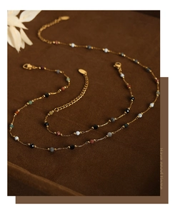 Detailed close-up of golden titanium steel chain with multi-color natural stone beads