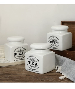 Detail of white ceramic storage canisters for sugar tea and coffee with vintage prints