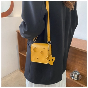 Detail shot of yellow cheese-shaped mini crossbody bag with a cute cheese pendant charm