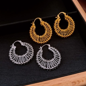 Detail of gold and silver woven hollow hoop earrings displayed in a black velvet jewelry box