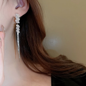 Detail of long tassel chain earrings with shimmering zircon crystals worn by a model