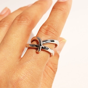 Polished silver knot ring with a unique intertwined double loop design on model's finger