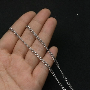 Close-up of a silver stainless steel Cuban link chain held in hand against black background