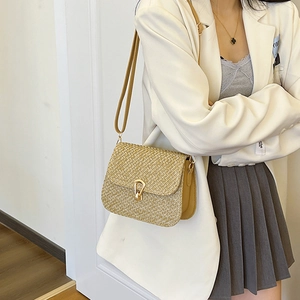 Handwoven straw crossbody bag with golden buckle and leather strap on model in suit
