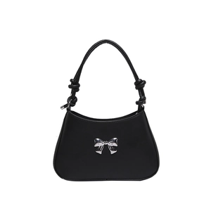 Chic black handbag with silver metal bow and knotted shoulder straps on white background