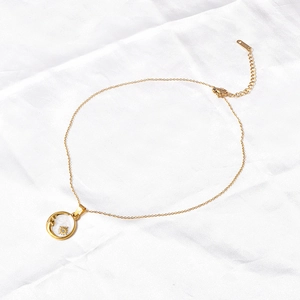 Detail of gold sun pendant with shell inlay and S925 clasp on white fabric