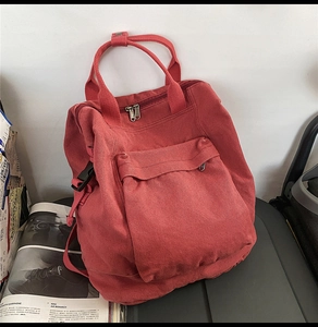 Detail of red canvas backpack with large front pocket and reinforced double handles