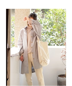 Close-up of a large beige canvas tote bag paired with a gray long shirt and casual trousers