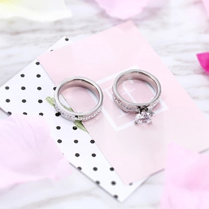 Silver tone solitaire engagement ring set with matching band on decorative petal background