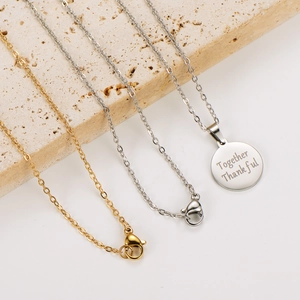Detailed shot of gold and silver stainless steel necklaces with engraved pendant on stone