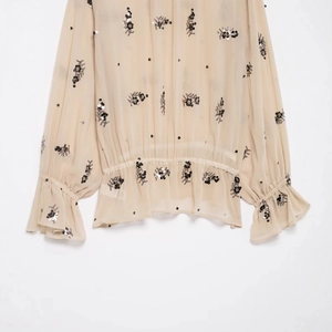Apricot sheer mesh long sleeve top with black floral sequins and ruffled cuffs
